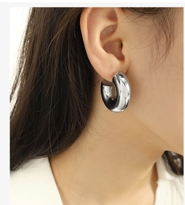 Close-up of polished silver C-shaped hoop earring worn by a model with a minimalist style
