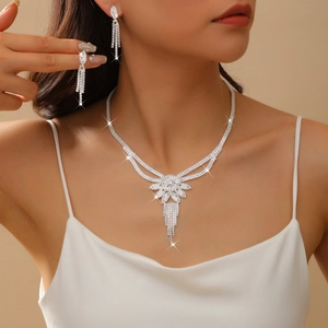 Close-up of elegant silver necklace set with rhinestones and long tassel earrings on a model