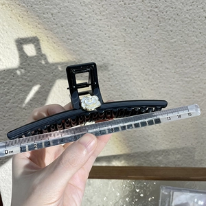 Detailed view of a 13cm black camellia hair claw clip measured with a ruler