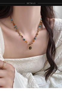 Gros plan d'un collier bohème avec perles en verre ambré et pendentif rond en métal