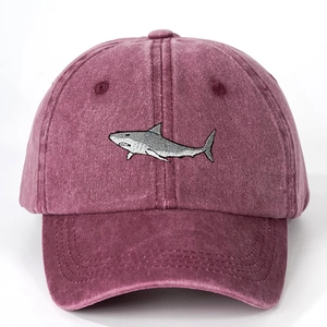 Close-up of a burgundy washed cotton baseball cap featuring detailed shark embroidery