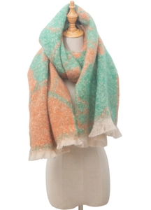 Close-up of jacquard knit scarf featuring green and orange floral patterns and white tassels