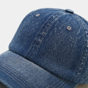 Macro detail of navy blue denim baseball cap showing premium stitching and fabric texture