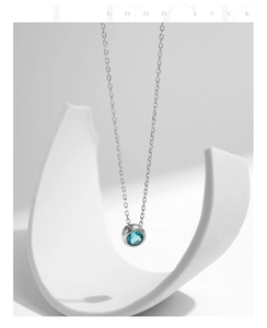 Close-up of s925 silver necklace with a round Paraiba blue gemstone pendant on a white prop
