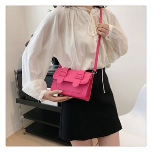 Detail of vibrant hot pink leather crossbody bag worn by a model in a minimalist setting