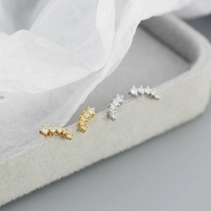 Close-up of gold and silver curved s925 sterling silver screw earrings with clear crystals