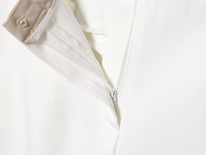 Detail of white trousers showing khaki waist lining and nylon zipper stitching