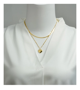 Detail of gold double-layered snake chain necklace with engraved heart pendant on white shirt