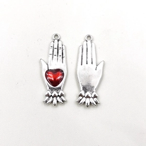 Detailed view of silver Gothic devil hand pendants with red heart inlay for DIY jewelry