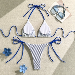 Detail of blue and white crochet knit bikini set with hollow texture on a beige background