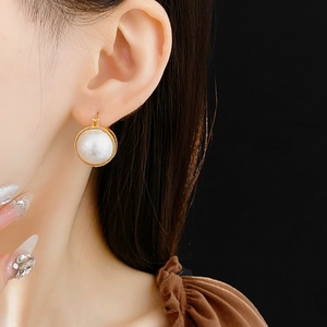 Gros plan d'une boucle d'oreille vintage en or avec perle blanche sur une femme