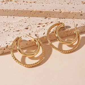 Detail of gold double-hoop earrings featuring one smooth and one braided textured ring