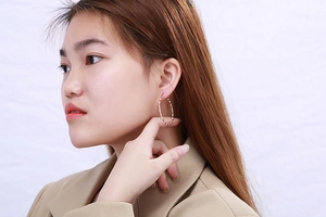 Close-up of elegant rose gold hoop earrings with twisted rope texture worn by a model