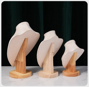 Three-piece beige velvet and beech wood necklace display set on marble surface