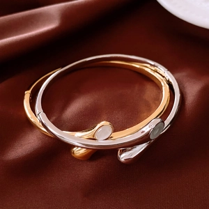 Detail of gold and silver tone bangles with white gemstones on dark brown satin fabric