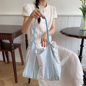 Close-up of floral canvas tote bag held by model in a minimalist aesthetic cafe setting