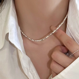 Gros plan d'un collier argenté avec perles carrées facettées sur le cou d'un mannequin