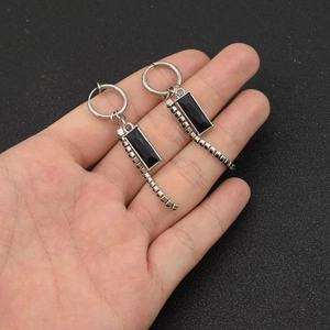Close-up of silver drop earrings with rectangular black stones and rhinestones