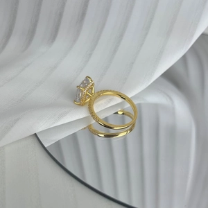 Macro shot of gold S925 silver ring with rectangle radiant-cut zircon on a reflective surface