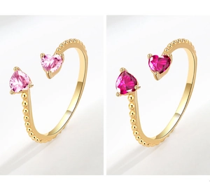 Close-up of heart-cut pink and magenta zircon gems on gold-plated beaded rings