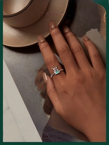 Close-up of reindeer ring with colorful zircons worn on finger in a cozy setting