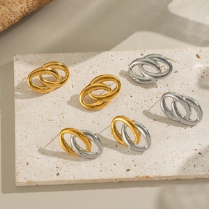 Dettaglio di orecchini a cerchio intrecciati in oro, argento e bicolore su base in pietra