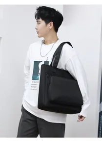 Model view of a large black waterproof nylon tote bag with front zipper pocket detail