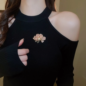 Detailed shot of a pink floral brooch with gold edges and pearl on a black sweater