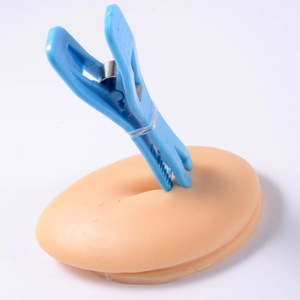 Detail view of acrylic piercing tool holding a silicone navel training model for practice