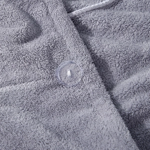 Detail of transparent button on thick grey coral fleece drying towel with soft texture
