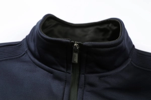 Gros plan du col montant et du zip métallique sur la veste de sport bleu marine