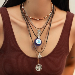Detail view of multi-layer boho necklace set with evil eye, tree of life and sun pendants