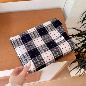 Close-up of checkerboard pattern makeup bag with red dots and side brand label