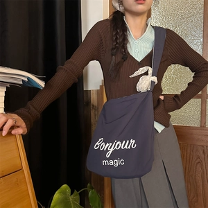 Detail of navy blue canvas bag with white Bonjour Magic text in a lifestyle setting
