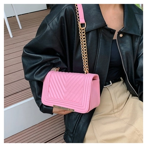 Detailed view of pink quilted handbag with chevron stitching and gold chain strap