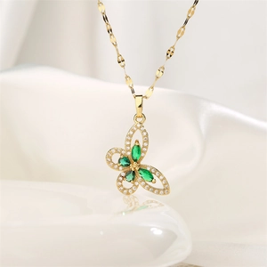 Close-up of gold butterfly pendant featuring green marquise stones and micro-pave crystals