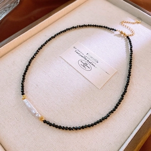 Close-up of baroque pearl and black beaded necklace on a velvet jewelry tray