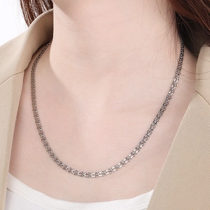 Close-up of polished stainless steel musical note necklace on model's neck