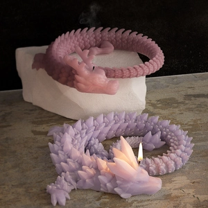 Dettaglio dello stampo per drago 3D con squame intricate su candele rosa e viola