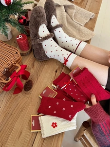 Festive red Christmas socks with bows and plush texture on a warm wooden table