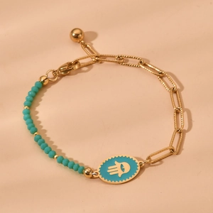 Detail of gold chain bracelet with turquoise beads and Hand of Fatima enamel charm
