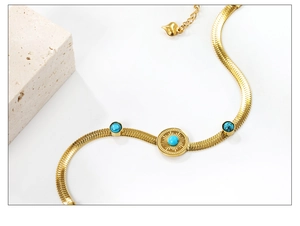 Details eines goldenen Schlangenarmbands mit Türkis-Inlay und Herz-Anhänger-Detail