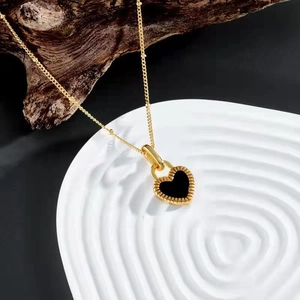 Close-up of heart pendant necklace with black shell inlay on a white pedestal display