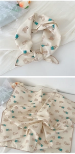 Detail of beige cotton linen scarf featuring cute rabbit patterns and brown stitched edges