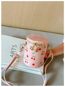 Detail of pink cherry print bucket bag showing floral metal zippers and adjustable strap