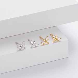 Macro detail of butterfly earrings with marquise-cut zircons in silver and gold finishes