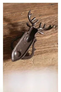 Vue détaillée d'un heurtoir de porte en fonte cerf vintage sur fond en bois rustique