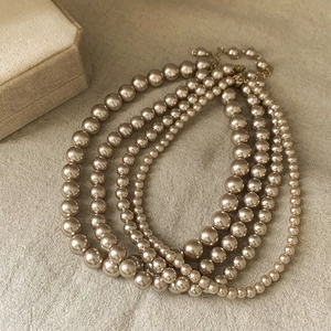 Flat lay of vintage multi-layered champagne pearl necklaces on linen background