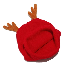 Detailed view of red knitted Christmas hat with plush reindeer antlers and ribbed texture