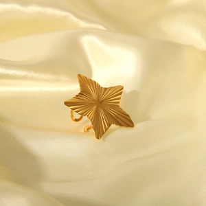 Golden star-shaped open ring with textured surface on a cream silk background